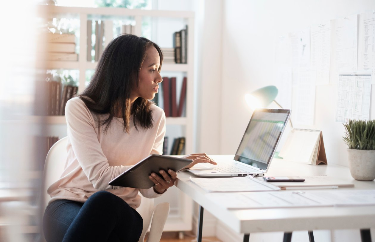 Person using a smartphone to manage budgeting and banking apps in a relaxed home setting.